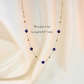 Nahaufnahme einer goldenen Edelstahlkette mit blauen Perlen auf weißem Stoff - Lapislazuli Halskette
