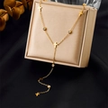 Dettaglio di una collana a Y dorata con ciondoli a croce e cristalli in un cofanetto - Stile Croce e Zircone (N2943)