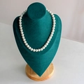 Elegant single layer white pearl necklace displayed on dark green velvet mannequin stand - Large Green Velvet