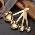 Golden heart-shaped measuring spoon set of 4 with engraved handles on dark counter - Gold