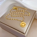 Minimalistische vergulde smiley ketting van titaniumstaal op een sieradendoos - Goud
