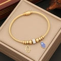 Golden spiral Hamsa Hand and Evil Eye charm bracelet displayed on a beige gift box - Fatima Hand Style(2#)