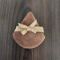 Brown velvet teardrop makeup puff with a beige satin bow ribbon on wood background - Brown