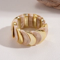 Vista macro di archi in metallo dorato e resina marmorizzata beige su un bracciale elastico - Bracciale - Beige