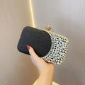 Detailed macro view of black glitter clutch with sparkling rhinestones and gold clasp - Black