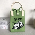 Detailed view of a green knitted panda phone bag with a cream handle and button closure - Panda Green
