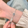 Silver evil eye bracelet with blue center stone and moonstone beads on wrist - Cat's Eye Evil Eye Silver Nuggets Bracelet