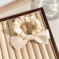 Cream silk scrunchie with a bow design and satin finish on a wooden jewelry tray - Solid Bow Decor Beige