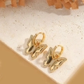 Makroaufnahme von goldenen Schmetterlingsohrringen mit Zirkonia auf Steinhintergrund - Schmetterling