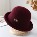 Detail of burgundy wool cloche hat with ARUHLT embroidery on a wooden stand - Burgundy