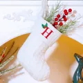 White knit Christmas stocking featuring red embroidered letter H and holly leaf detail - Letter H / White
