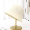 Close-up of cream knitted bucket hat showing breathable crochet texture on a gold stand - Creamy White