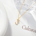 Macro shot of gold letter J pendant with a zircon floral detail on a white surface - Letter J