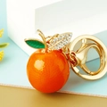 Detailed view of orange cherry keychain with sparkling rhinestones and golden leaf accents - Big Orange