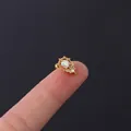 Gold stainless steel ear stud with colorful AB zircon gemstone on a fingertip - Floral Leaf Aurora Gemstone Style (HSPJ308-8#G)