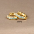Macro view of 7mm gold hoop earrings featuring a single row of tiny sky blue zircon stones - 7mm / Gold (Blue Zircon)