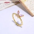 Close-up of gold butterfly ring with pink crystals and twisted band detail on vintage paper - Gold Pink Zirconia Rope Band Butterfly(ZYN-DMR118G-1)