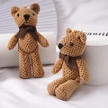 Brown knitted teddy bear keychain with dark brown ribbon bow on white display stand - Brown