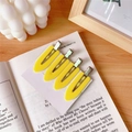 Set of 4 yellow shield-shaped seamless hair clips displayed on a card with a vintage book - Yellow