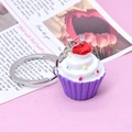 Detalle de un llavero de cupcake morado con crema blanca, corazón rojo y virutas de colores - Morado