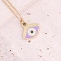 Macro shot of gold evil eye necklace with purple enamel detail on a beige stone surface - Purple
