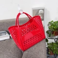 Close-up of a red hollow-out woven jelly tote bag with ergonomic round double handles - Small Red