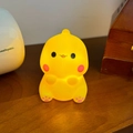 Yellow dinosaur LED night light with warm glow on wooden desk for children - Smiling Dragon White