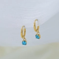Elegant gold hoop earrings with a sky blue zircon pendant on white fabric background - Aqua