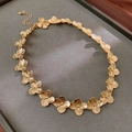 Dettaglio macro di una collana a fiore dorata con trama in metallo spazzolato su velluto - Collana / Collana - Oro