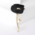 Vista dettagliata di un'elegante spilla a fiore nero e oro su sfondo geometrico bianco - Nero