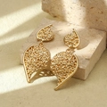 Detailed view of golden leaf-shaped earrings with textured finish on a stone - Gold