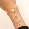 Gros plan du bracelet rosaire doré avec médaille de la Vierge Marie et croix en diamant - Chapelet Or - Perle Blanche