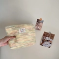 Dettaglio della borsa da trucco in peluche a righe colorate con toppa logo e trama morbida - Giallo