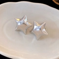 Detailed view of silver star earrings placed on a minimalist white ceramic jewelry tray - Silver Star Shape