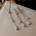 Makroaufnahme von silbernem Wassertropfen-Quasten-Halsketten- und Ohrring-Set auf Tablett - Halsketten- und Ohrring-Set / Silber