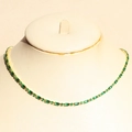 Elegant gold-plated jewelry set with emerald green zircons on a beige mannequin bust - Necklace