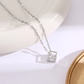 Gros plan du collier en acier argenté avec pendentif cube évidé et zircon étincelant - Collier diamant carré creux / Argenté