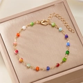 Golden delicate beaded bracelet with colorful charms on a beige premium jewelry box lid - 007 Seed Bead / Bracelet
