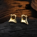 Orecchini a cerchio trapezoidali dorati lucidi per donna su sfondo di legno scuro - Oro