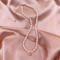 Elegant natural freshwater pearl necklace with golden spherical pendant on silk background - Gold Bead Necklace