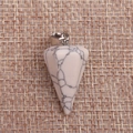 Macro shot of white turquoise cone pendant with black veins on rustic burlap fabric - White Turquoise