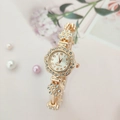 Close-up of a floral gold watch with rhinestones and a quartz dial on a pink background - Rose Gold Case White Dial