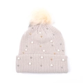 Dettaglio di cappello in maglia con pompon di pelliccia, perle bianche e dorate - Bianco