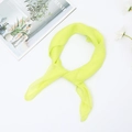 Detail of yellow-green chiffon square scarf knot on a magazine and white flower backdrop - Cyan
