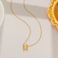 Macro detail of a gold titanium necklace featuring a crystal-encrusted H-shaped pendant - Iced Out H Style (8806) / Gold