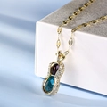 Peanut-shaped gold pendant necklace with purple and blue gemstones on white box - Gold Peanut Gemstone