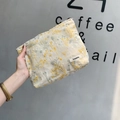 Nahaufnahme der beigen Stofftasche mit Blumenstickerei, in der Hand gehalten vor grauer Wand - Beige