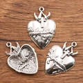 Three silver metal sacred heart charms with cross and thorns on wood background - 27B2-6 Thorns Sacred Heart