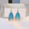 Macro shot of iridescent cicada earrings with intricate hollow wings on jewelry box - Iridescent Cicada