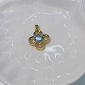 Elegant gold four-leaf clover pendant with inset zircons on a white ceramic dish - Four-Leaf Clover